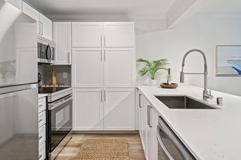 A kitchen with white cabinets and a stainless steel sink.